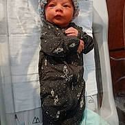 Maverick is registered to the contest to win money with this photo: newborn, baby, infant, onesie, hat, bassinet, blanket, clothing, face, person, lying_down, indoors, cute, sleepwear, baby_bedding, portrait, child, sleeping_area, soft, newborn_clothes