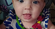 Coraline joined the competition — help win amazing prizes! baby, infant, child, portrait, face, eyes, tongue, looking_at_camera, striped_clothing, blue, white, colorful, necklace, toy, cartoon, indoor, bedding, close_up, sitting, cute