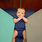 Coraline joined the competition — help win amazing prizes! baby, child, infant, portrait, smiling, happy, sitting, lying_down, hands, face, blue_outfit, patterned_clothing, socks, shoes, changing_pad, indoor, wooden_background, colorful_panels, photography, safe