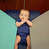 baby, child, infant, portrait, smiling, happy, sitting, lying_down, hands, face, blue_outfit, patterned_clothing, socks, shoes, changing_pad, indoor, wooden_background, colorful_panels, photography, safe