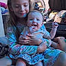 children, baby, sibling, sister, infant, smiling, portrait, sitting, indoors, family, hugging, holding, long_hair, floral_clothing, baby_clothing, fan, toys, laundry, home, candid
