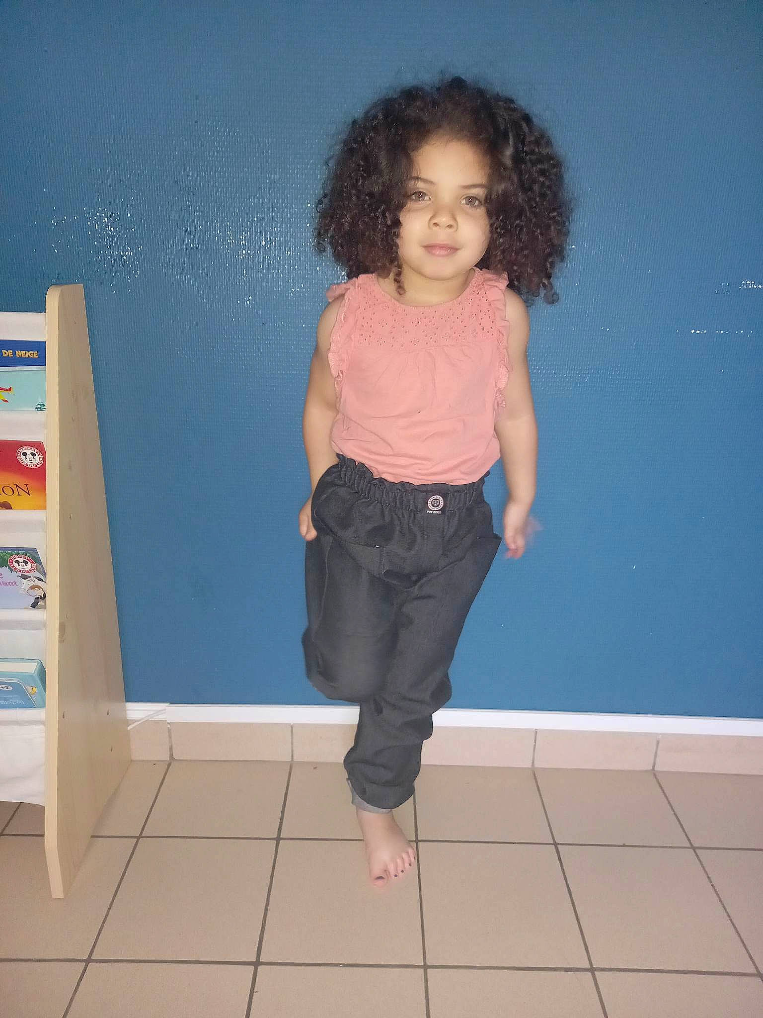 Inaya participe au concours pour gagner de l'argent avec cette photo : bookcase, denim, electric_blue, fashion_design, flooring, fun, hair, human_leg, joint, knee, magenta, pattern, person, shelf, sitting, smile, standing, t_shirt, thigh, trunk