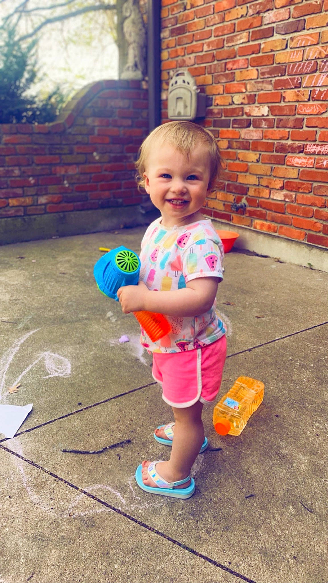 Charli is registered to the contest to win money with this photo: asphalt, baby_toddler_clothing, brick, brickwork, child, door, fun, grass, hairstyle, happy, joy, leisure, person, pink, public_space, recreation, shorts, smile, standing, t_shirt