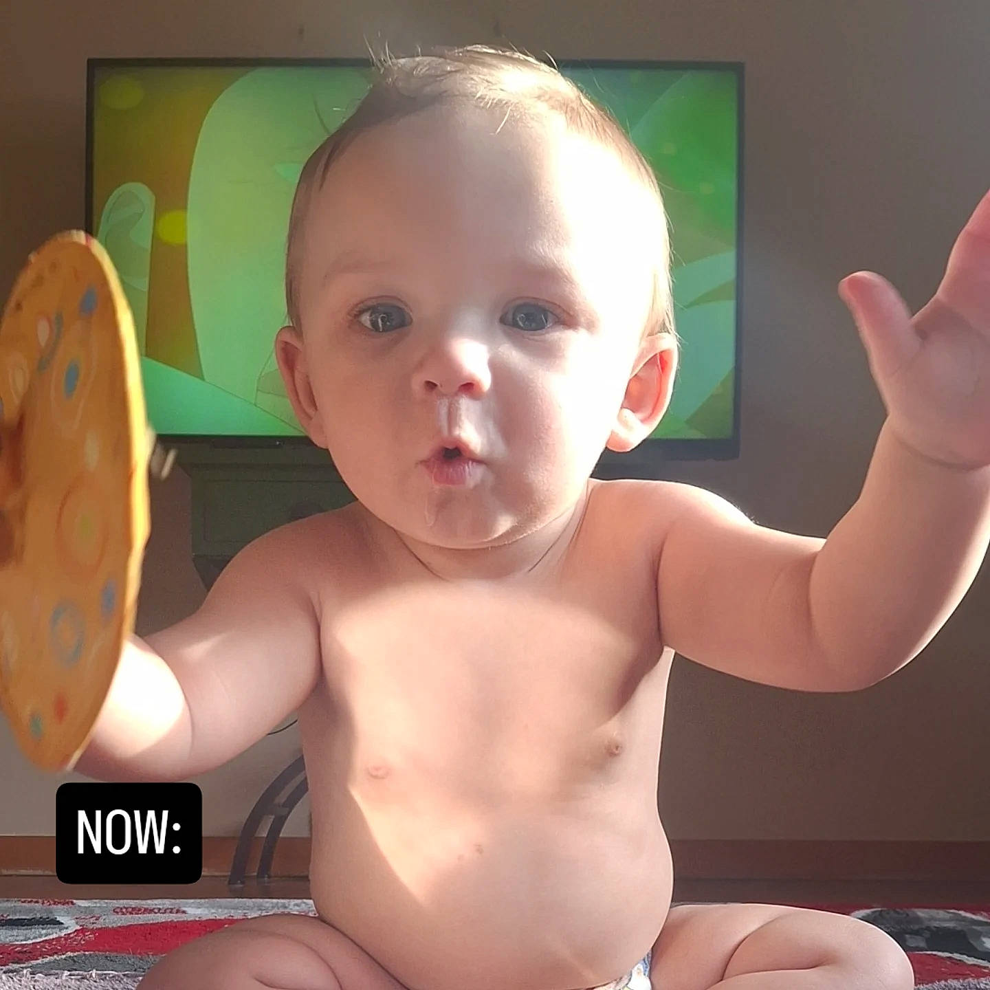 baby, carpet, cartoon, child, curious, diaper, expression, face, hand, indoor, light, play, room, shadow, shirtless, sitting, skin, television, toy, young