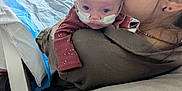 Matilda joined the competition — help win amazing prizes! baby, woman, hospital, oxygen_tube, kiss, affection, indoor, medical, care, face, person, clothing, sitting, blanket, furniture, head, skin, comfort, support, love