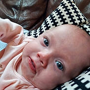 Matilda is registered to the contest to win money with this photo: baby, infant, face, closeup, pink_clothing, blue_eyes, drool, pillow, patterned_pillow, leather_couch, indoor, person, child, cute, young, portrait, skin, head, expression, resting