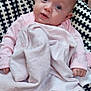 baby, infant, blanket, pink_clothing, blue_eyes, curious_expression, barefoot, cushion, patterned_fabric, indoors, soft_texture, child, cute, small_hands, small_feet, seated, comfort, looking_up, human, portrait