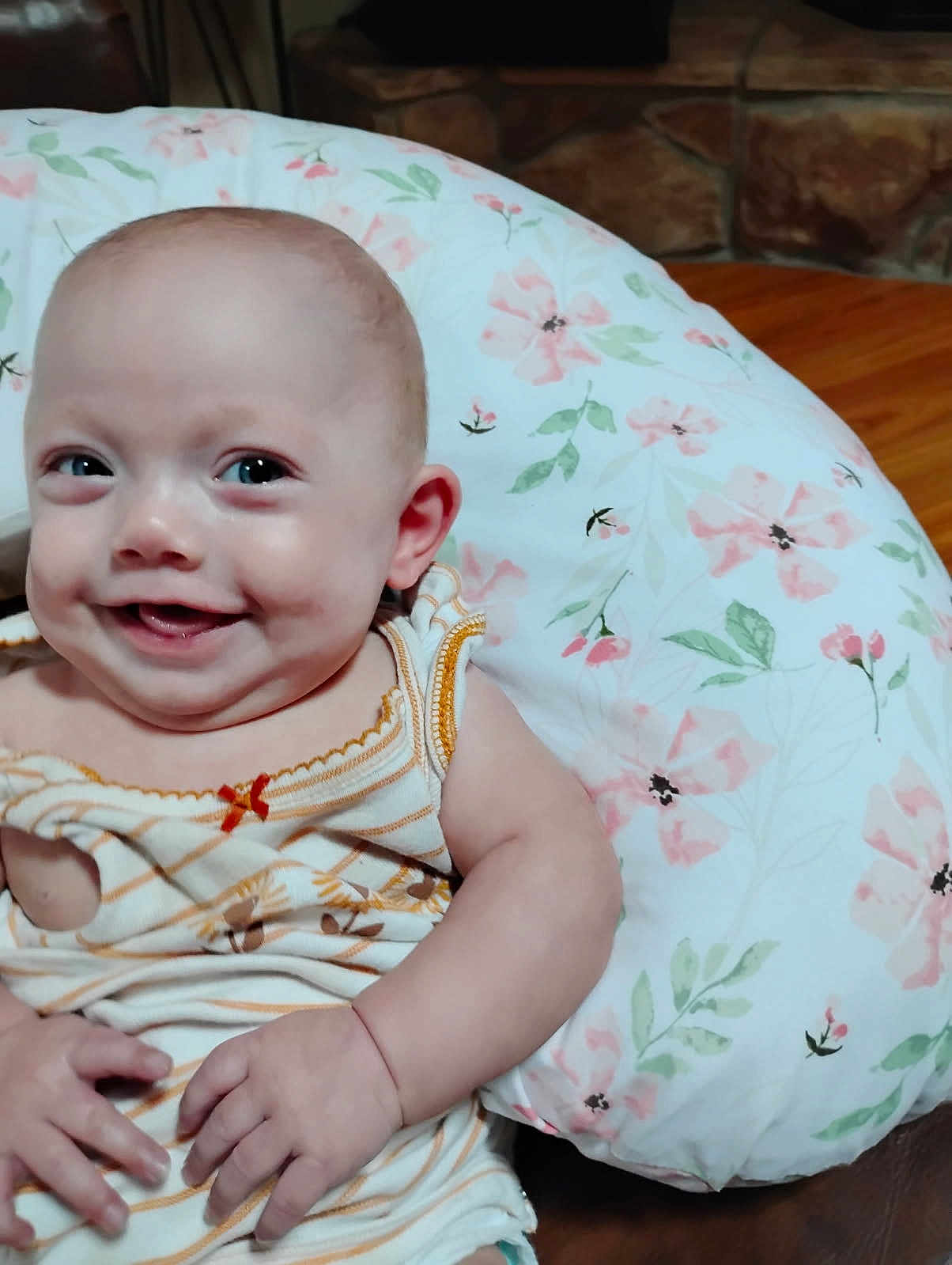 Matilda is registered to the contest to win money with this photo: baby, smiling, infant, child, pillow, floral_pattern, clothing, striped_outfit, cute, happy, indoors, face, hand, skin, sitting, portrait, young_child, comfort, couch, background