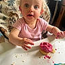 Oaklynn-Ayla is registered to the contest to win money with this photo: toddler, child, baby, high_chair, cupcake, frosting, pink_frosting, cake, messy_eating, food, dessert, smiling, wide_eyed, blonde_hair, pink_shirt, indoor, portrait, sitting, dining, candid