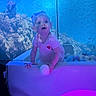 Oaklynn-Ayla is registered to the contest to win money with this photo: child, toddler, baby, portrait, sitting, curious, indoors, aquarium, underwater_theme, blue_lighting, purple_lighting, ball_pit, play_area, pink_shirt, heart_design, short_hair, smiling, looking_at_camera, playful, colorful