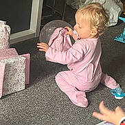 Oaklynn-Ayla joined the competition — help win amazing prizes! child, toddler, baby, sitting, kneeling, pink_outfit, pacifier, blonde_hair, profile, indoor, carpet, presents, wrapping_paper, gift_boxes, toy, playtime, home, celebration, hands, portrait