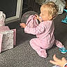 baby, blonde_hair, carpet, celebration, child, gift_boxes, hands, home, indoor, kneeling, pacifier, pink_outfit, playtime, portrait, presents, profile, sitting, toddler, toy, wrapping_paper