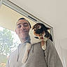 Saphir participe au concours pour gagner de l'argent avec cette photo : man, cat, calico_cat, hoodie, shoulder, indoor, window, tree, smile, pet, feline, casual_clothing, human, light, daylight, happy, portrait, animal, friendship, relaxed