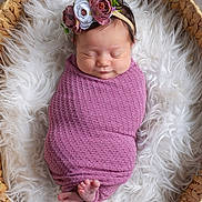 Bailey is registered to the contest to win money with this photo: newborn, baby, sleeping, wrapped, purple_blanket, floral_headband, basket, woven_basket, white_fur, soft_texture, cozy, peaceful, infant, cute, portrait, indoors, feet, head, face, sleep