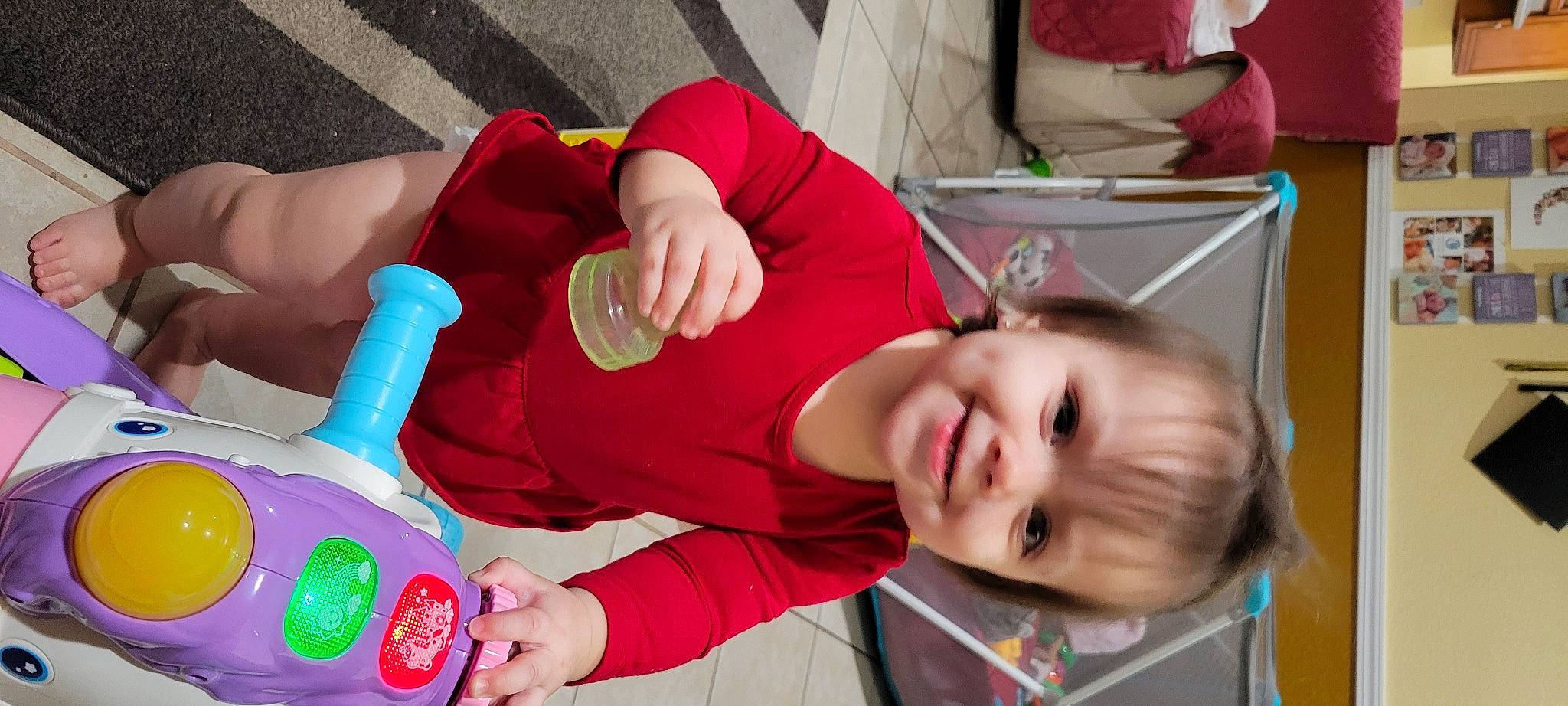 Daniella is registered to the contest to win money with this photo: baby, baby_products, baby_toddler_clothing, child, finger, fun, happy, human_leg, joy, mouth, nail, party, person, play, red, room, sitting, smile, t_shirt, toddler