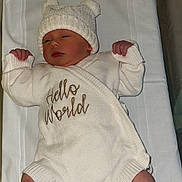 Willow is registered to the contest to win money with this photo: newborn, baby, infant, knit_hat, white_clothing, hospital_bassinet, sleeping, cute, soft_texture, socks, baby_clothes, peaceful, lying_down, baby_bassinet, child, portrait, indoors, text_on_clothing, white_background, warm