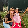 Arianna joined the competition — help win amazing prizes! woman, toddler, child, slide, outdoor, playground, grass, tattoo, smile, dress, pink, footwear, casual_clothing, nature, tree, fence, happy, family, play, daytime