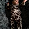 baby, infant, onesie, leopard_print, footed_pajamas, blanket, soft_texture, lying_down, hand, face, cute, child, sleepwear, cozy, indoor, portrait, newborn, expression, skin, person