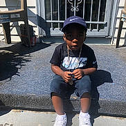Caderion joined the competition — help win amazing prizes! child, boy, nike, cap, tshirt, chain, sneakers, white_shoes, sitting, doorstep, shadow, outdoor, concrete, plastic_chair, metal_door, carpet, sunlight, serious_expression, person, casual_clothing