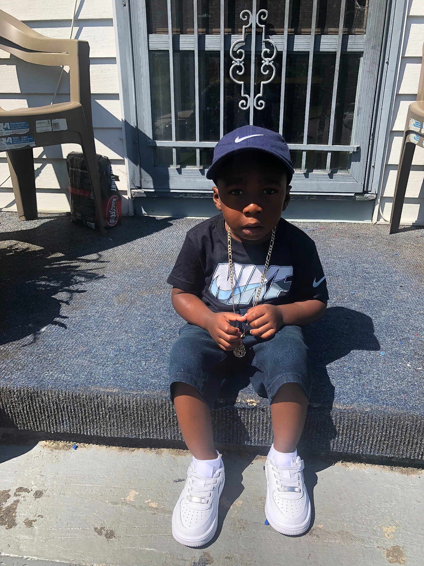 Caderion joined the competition — help win amazing prizes! child, boy, nike, cap, tshirt, chain, sneakers, white_shoes, sitting, doorstep, shadow, outdoor, concrete, plastic_chair, metal_door, carpet, sunlight, serious_expression, person, casual_clothing