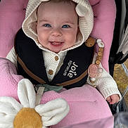 Olivia is registered to the contest to win money with this photo: baby, smiling, knitted_hoodie, bear_ears, pink_blanket, stroller, plush_toy, pacifier, baby_clothing, child, happy, cute, infant, seat_harness, wooden_beads, toy_flower, closeup, face, portrait, baby_accessories