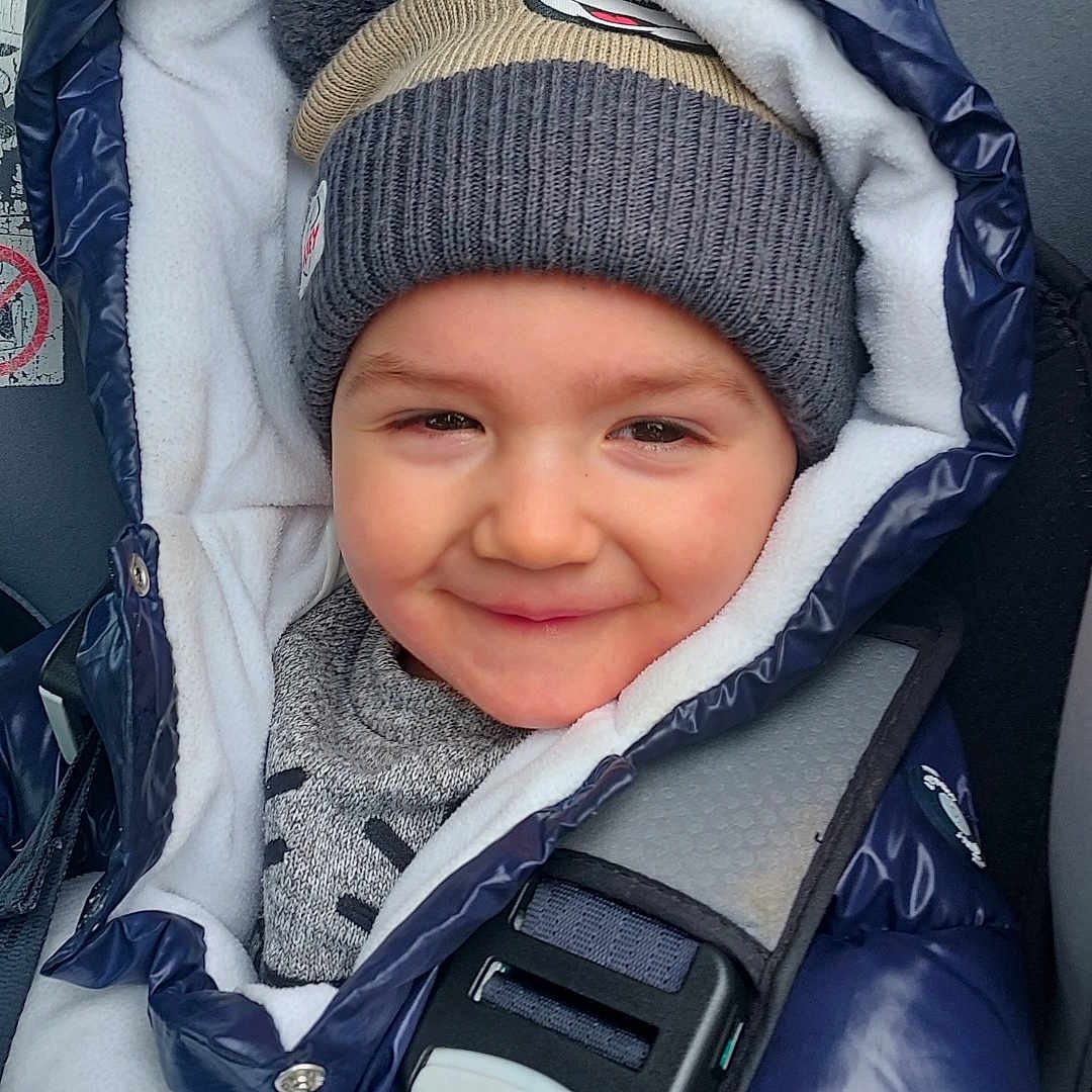Maël participe au concours pour gagner de l'argent avec cette photo : accessories, baby, bonnet, cap, car, clothing, coat, face, glove, hat, head, hood, jacket, lifejacket, pants, person, photography, portrait, transportation, vest