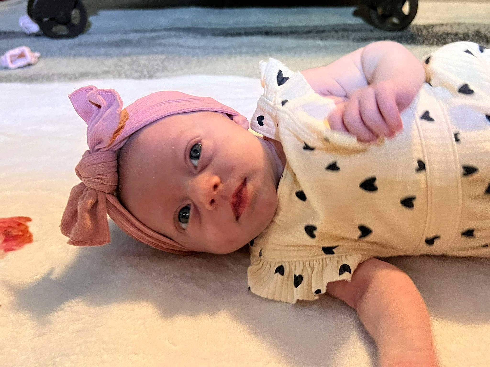 Oaklynn is registered to the contest to win money with this photo: baby, baby_toddler_clothing, cheek, child, flooring, foot, fun, fur, head, pattern, person, sitting, skin, sleeve, textile, tire, toddler, toy, wheel, wood