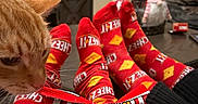 Carrot joined the competition — help win amazing prizes! cat, orange_cat, cheez_it, snack, socks, matching_socks, feet, living_room, couch, gnome, decor, cozy, crackers, packaging, red, person, hand, table, furniture, indoor