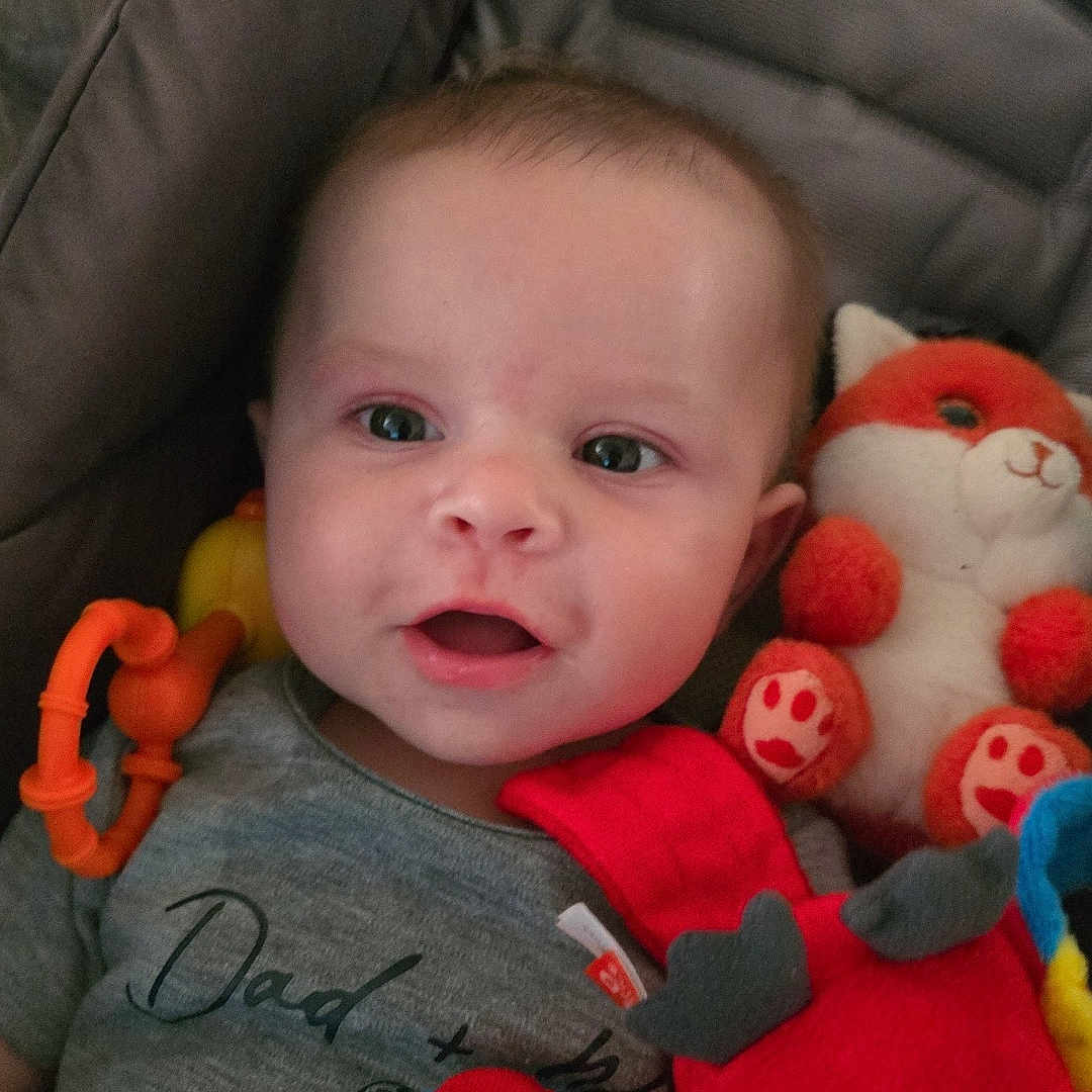 Mayron a rejoint le concours — aidez-le/la à gagner de superbes lots ! baby, baby_toys, child, closeup, clothing, cushion, eyes, face, fox_toy, happy, indoor, infant, motorcycle_print, pacifier, plush_toy, red_toy, shirt, smiling, soft_toys, text_on_clothing