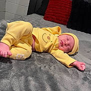 Oaklynn joined the competition — help win amazing prizes! baby, bare_feet, bed, bedroom, black_pillow, blanket, brick_wall, gray_bedding, hood, infant, lying_down, newborn, onesie, peaceful, pillow, portrait, red_pillow, sleeping, smiley_face, yellow_outfit