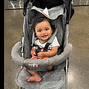 Jonnathan joined the competition — help win amazing prizes! baby, stroller, smiling, indoor, laundromat, washing_machine, clothing, footwear, floor, seat, baby_clothes, happy, child, infant, person, toddler, toy, handlebar, fabric, black_hair