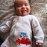 Xavier joined the competition — help win amazing prizes! baby, infant, smiling, onesie, clothing, red_crab, text, blanket, soft_texture, cute, lying_down, happy, child, face, hand, pajamas, cozy, indoor, portrait, casual