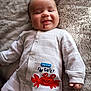 baby, infant, smiling, onesie, clothing, red_crab, text, blanket, soft_texture, cute, lying_down, happy, child, face, hand, pajamas, cozy, indoor, portrait, casual