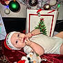 baby, infant, child, candy_cane, santa_hat, christmas_tree, ornament, gift_bag, plush_toy, holiday, festive, lying_down, blanket, onesie, blue_eyes, red_decor, tree_skirt, decorations, face, person