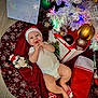 baby, infant, christmas, christmas_tree, ornament, candy_cane, stocking, santa_hat, smile, festive, gift_bag, tree_skirt, red, white, plush_toy, baby_clothes, hardwood_floor, holiday_card, celebration, feet