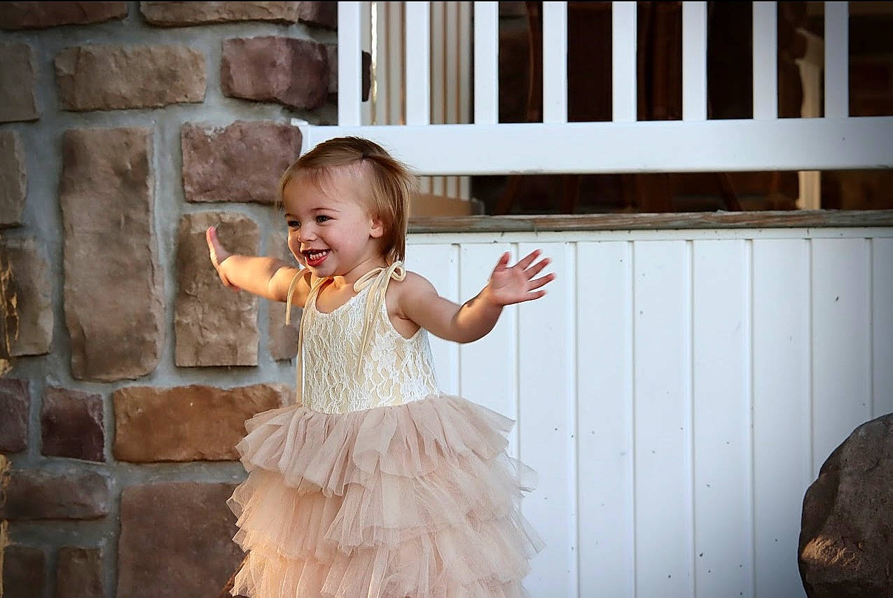 Hanna is registered to the contest to win money with this photo: baby, baby_toddler_clothing, bridal_clothing, child, day_dress, door, dress, event, eye, flash_photography, formal_wear, fun, happy, joy, person, ruffle, sleeve, smile, standing, toddler