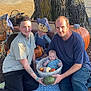 family, baby, adult, tree, pumpkin, scarecrow, blanket, outdoor, grass, autumn, fall, basket, smile, tattoo, blue_clothing, green_gourd, sunlight, nature, people, happy
