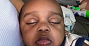 Josiah joined the competition — help win amazing prizes! baby, sleeping, close_up, indoor, couch, person, child, living_room, water_bottle, toy, shirt, leather_couch, household_items, relaxing, home, infant, face, comfort, resting, nap