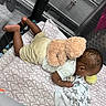 baby, teddy_bear, playpen, blanket, toy, infant, child, fabric, soft, crawling, floor, pattern, home, indoors, person, cute, sleeping_area, childcare, resting, comfort