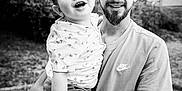 Mayron a rejoint le concours — aidez-le/la à gagner de superbes lots ! child, toddler, man, tattoo, smile, outdoor, black_and_white, happy, holding, person, casual_clothing, short_hair, beard, nature, grass, footwear, tree, portrait, family, love