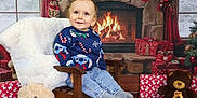 Kelyan participe au concours pour gagner de l'argent avec cette photo : blanket, blue_sweater, child, christmas_decor, curtains, festive, fireplace, holiday, indoor, jeans, plush_toy, smiling, socks, stockings, sweater, teddy_bear, toddler, wooden_chair, wrapped_gifts, wreath