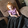Andie is registered to the contest to win money with this photo: child, toddler, red_hair, blanket, armchair, purple_shirt, indoor, cozy, laptop, curly_hair, smiling, blue_eyes, furniture, home, relaxing, person, portrait, casual, seated, comfortable