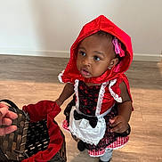 Kamya joined the competition — help win amazing prizes! toddler, child, costume, red_hood, basket, indoor, floor, curious, portrait, black_socks, lace, dress, hand, person, looking_up, girl, hair_clips, playful, young_child, bright_colors
