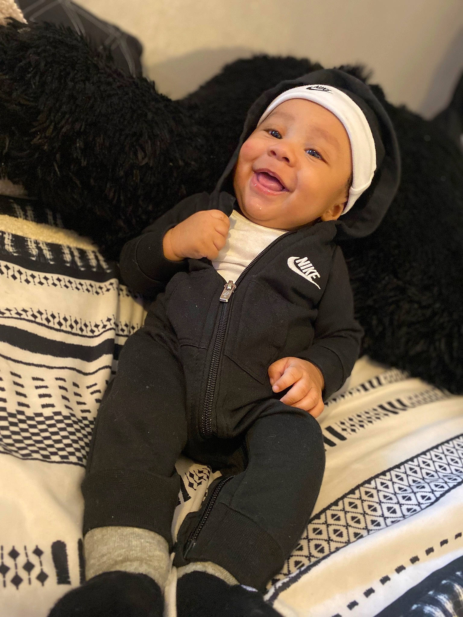 Dakari is registered to the contest to win money with this photo: baby, bag, black_hair, comfort, cool, fashion, flash_photography, fur, hairstyle, happy, headwear, human_leg, knee, leggings, luggage_and_bags, outerwear, person, sitting, smile, textile