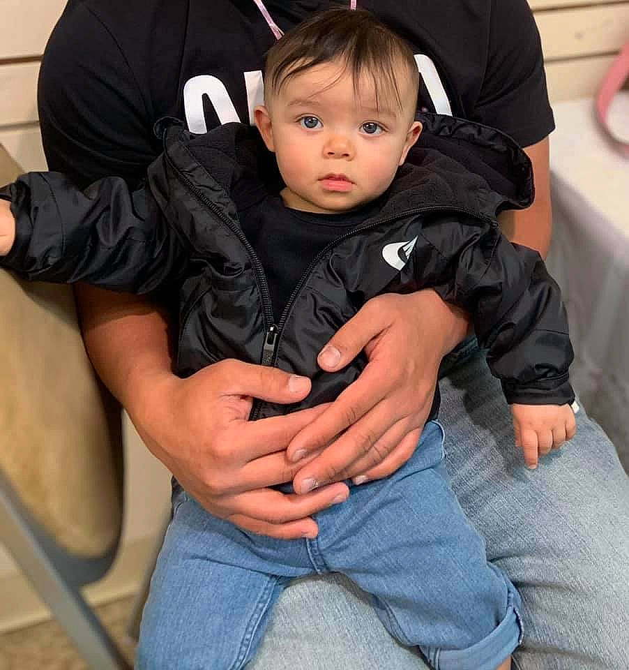 Nehemias is registered to the contest to win money with this photo: arm, baby_toddler_clothing, black_hair, chair, cheek, child, comfort, eye, finger, gesture, hand, head, joint, lap, leg, person, skin, sleeve, thigh, thumb