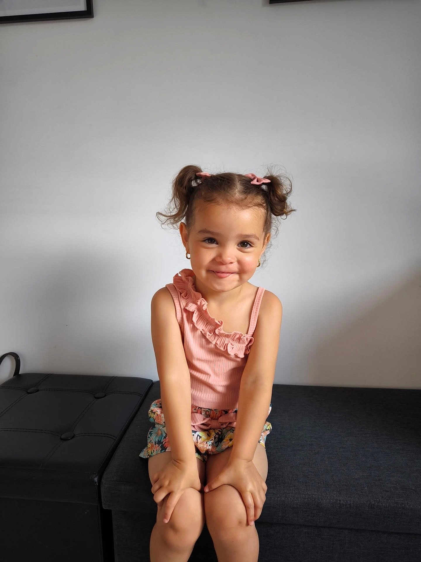 Giuliana a rejoint le concours — aidez-le/la à gagner de superbes lots ! child, girl, pigtails, pink_bows, smile, sitting, bench, floral_shorts, pink_top, indoor, cute, portrait, happy, minimalist, fashion, young, hands, face, hairstyle, casual