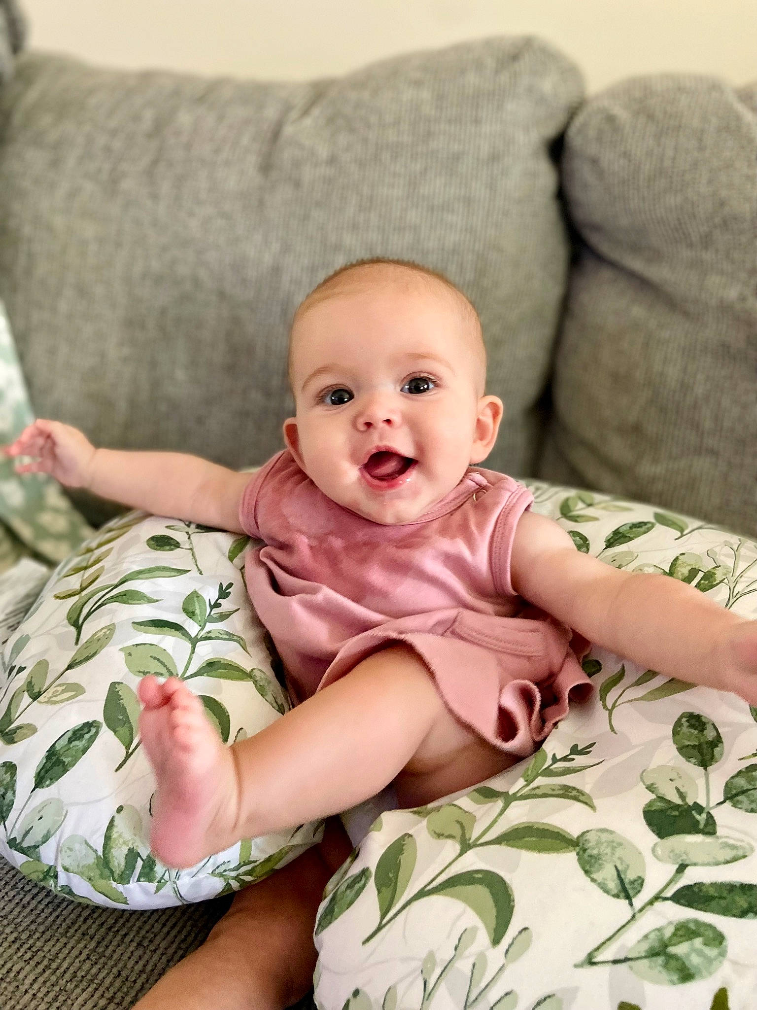 Lennon is registered to the contest to win money with this photo: baby, baby_toddler_clothing, cheek, child, comfort, couch, eye, face, happy, head, human_leg, iris, linens, pattern, person, sitting, skin, sleeve, smile, stomach