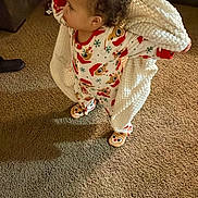 Ivy is registered to the contest to win money with this photo: toddler, child, pajamas, reindeer, blanket, carpet, slippers, living_room, curly_hair, standing, cozy, indoor, furniture, couch, baby, person, cute, warm, holiday_theme, home