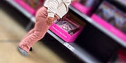 Ivy joined the competition — help win amazing prizes! toddler, child, curly_hair, clothing, sweatshirt, pants, socks, store, aisle, shelf, valentines_day, cards, pink, box, floor, indoor, shopping, blurred_background, exploring, curious
