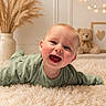 baby, smiling, infant, toddler, green_clothing, fluffy_rug, teddy_bear, nursery, string_lights, cozy, happy, cute, indoors, child, portrait, soft_lighting, decor, warm_colors, face, crawling